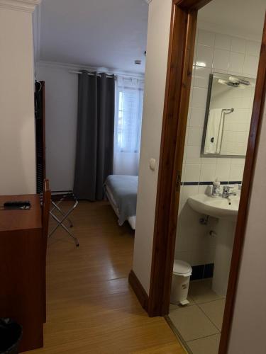 a bathroom with a sink and a bed and a mirror at Hospedaria Insular in Ponta Delgada