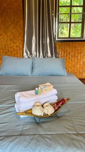 a tray with towels and other items on a bed at ริมแควโฮมสเตย์ กาญจนบุรี in Ban Pong Pat