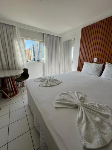 a bedroom with a white bed with a dress on it at Ponta Negra Flat 305 in Natal