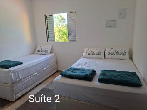 two twin beds in a room with a window at Chácara Solar de Jarinu in Jarinu