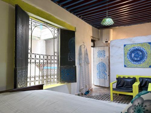 a bedroom with a bed and a window and a chair at Hostel Dar Caftan in Fez