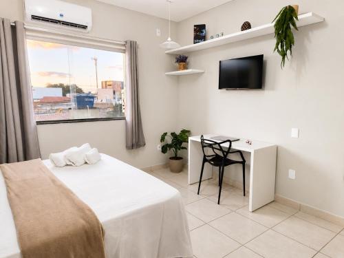 a bedroom with a bed and a table and a window at Isa Flats in Janaúba