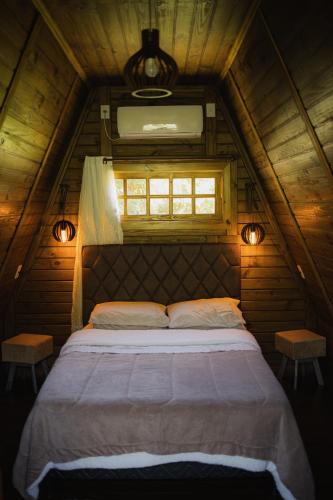 a bed in a wooden room with a window at Chalé de Madeira em Vargem Alta in Vargem Alta