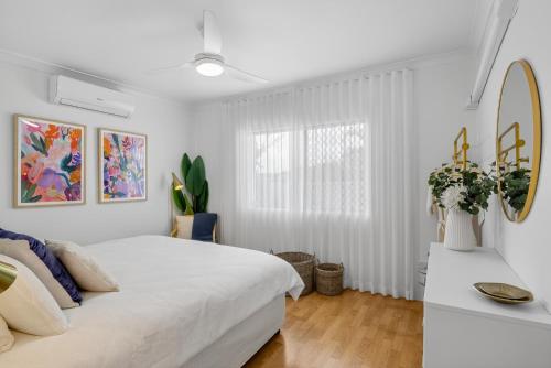a white bedroom with a bed and a window at Boutique Bribie Stay in Bellara