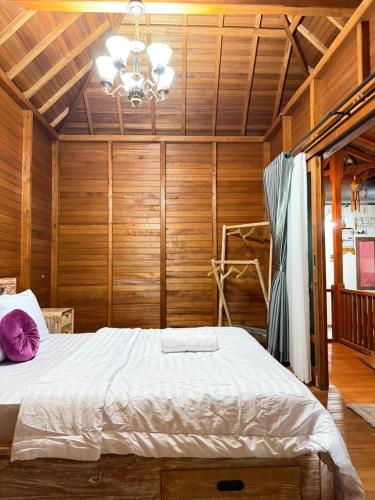 a bedroom with a bed with wooden walls and a chandelier at Pondok Nisya in Sawan