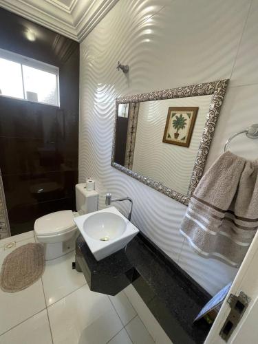 a bathroom with a sink and a toilet and a mirror at Sobrado Savana in Foz do Iguaçu