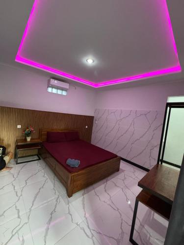 a bedroom with a bed with a pink lighting at Penginapan Angsoka 1 in Singaraja
