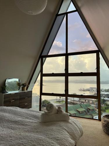 a bedroom with a large window with a bed and a television at Moana View in Paihia