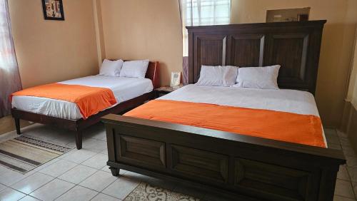 a bedroom with two beds and an orange blanket at Smithy's Apartment 1 in Brighton Village