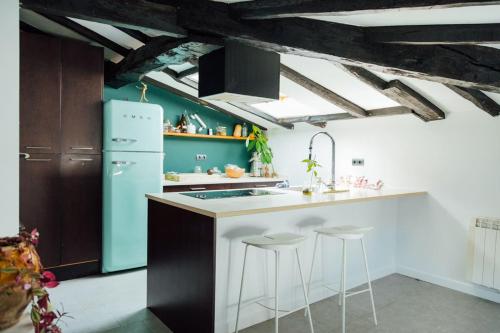 a kitchen with a blue refrigerator and bar stools at GOZATEGI - Photo studio in Irún