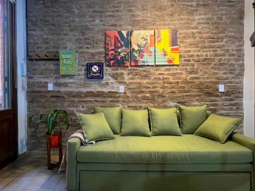 a green couch in a room with a brick wall at Loft con patio frente a Mercado San Telmo, 2 baños in Buenos Aires