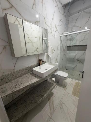 a white bathroom with a sink and a toilet at casa da piscina e churrasco in Maringá