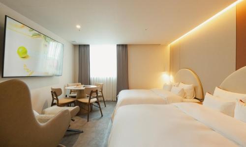 a hotel room with two beds and a table at Brown Dot Hotel Andong Taehwa in Andong