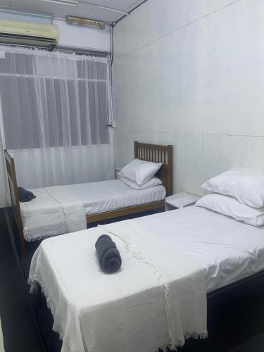 a room with two beds with white sheets at Sejiwo Apartment 6-8pax in Pengkalan Cepa