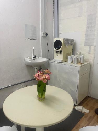 a bathroom with a table and a sink and a vase with flowers at Sejiwo Apartment 6-8pax in Pengkalan Cepa