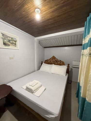 a small bedroom with a white bed with a wooden ceiling at LD Ignacio Island Resort in Roxas