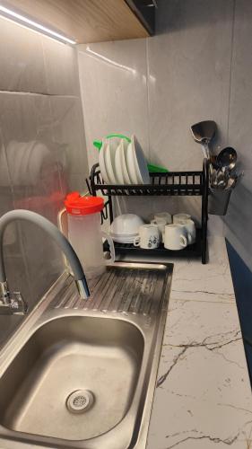 a kitchen sink with plates and cups on a shelf at Departamento Confortable in Latacunga