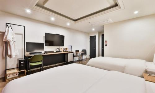 a hotel room with two beds and a desk at Beyond Hotel in Incheon