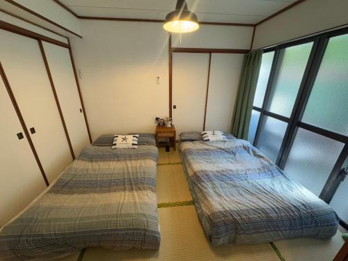 two beds sitting in a room with windows at Green Hights Residence-106 in Naha