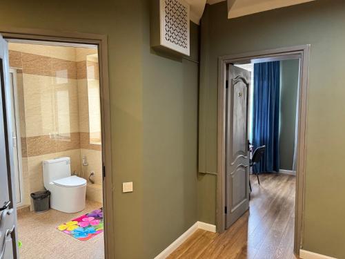 a bathroom with a toilet and a door open at Ricco guest house in Bishkek
