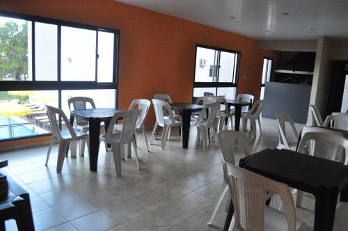 a restaurant with tables and white chairs and windows at Los Abus in Colón