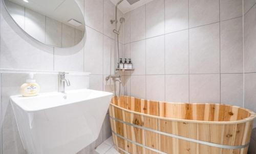 a bathroom with a wooden tub next to a sink at Brown Dot Hotel NamGumi in Yangji-mal