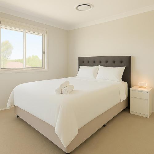 a white bedroom with a large white bed with two pillows at Emmaus Hill in Blue Haven