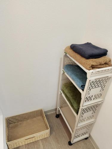 a white shelf with towels on it next to a wall at Villa Koedo in Kawagoe