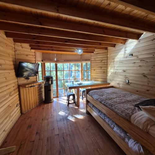 a room with a bed and a table in a cabin at Lodge De Ñuble in Las Trancas