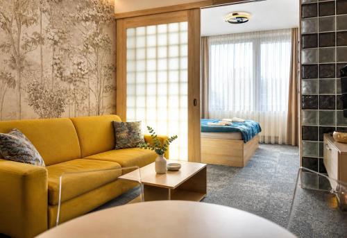a living room with a yellow couch and a bed at Apartment Elegance Hrebienok in Starý Smokovec
