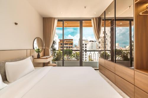 a bedroom with a large white bed and large windows at My Khe Hotel in Danang