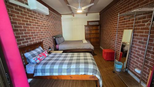 a small room with a bed and a brick wall at Peaceful Haven Guest House, in Adelaide