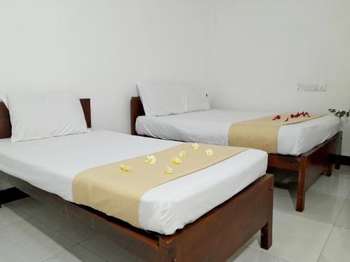 two beds with flowers on them in a room at DA GREA NATURAL BEACH HOTEL in Trincomalee