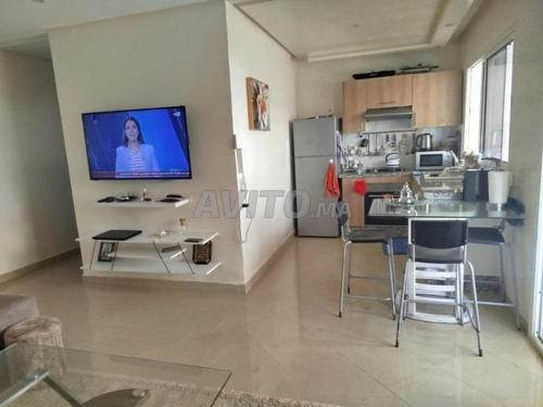 a living room with a kitchen with a tv on the wall at mona in Sidi Rahal