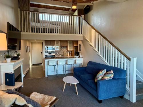 a living room with a blue couch and a kitchen at Oceanfront Studio with Loft - amazing views! in Qualicum Beach