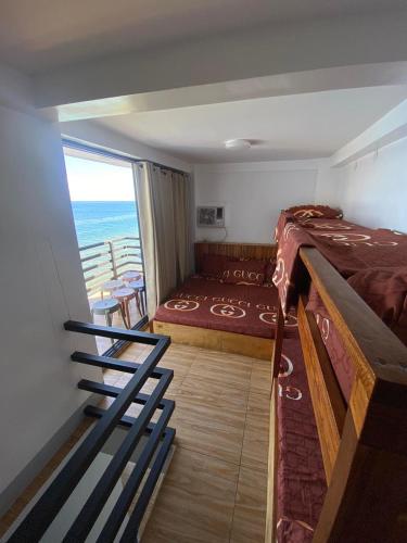 a bedroom with a bed and a balcony with the ocean at Cliff Cabanas by Hiverooms in Catmon
