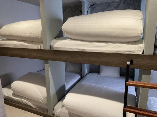 a stack of white pillows on a shelf at ピンポンホテル Peace Park in Hiroshima