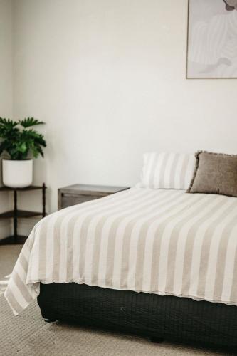 a bedroom with a bed with a striped blanket at Heritage Hideaway in Bunbury