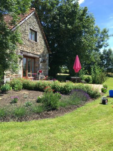 una casa de piedra con una sombrilla rosa en el patio en Gites du Manoir, en Runan