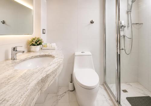 a bathroom with a toilet and a sink and a shower at Chelsea Hotel Abuja in Abuja