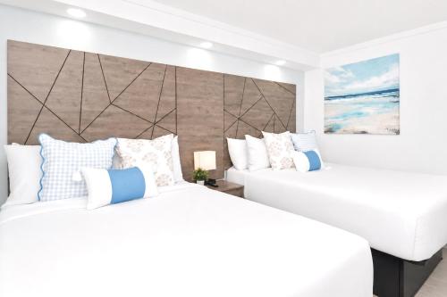 two beds in a bedroom with white and blue pillows at Fin's Inn & Suites in Myrtle Beach