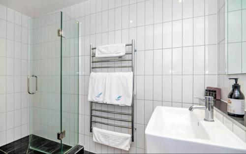 a white tiled bathroom with a sink and a shower at Ohope Beach Resort in Ohope Beach