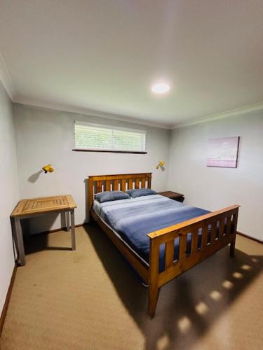 a bedroom with a wooden bed and a table at Stouty's at Hat Head - No Sheets or Towels Provided in Hat Head