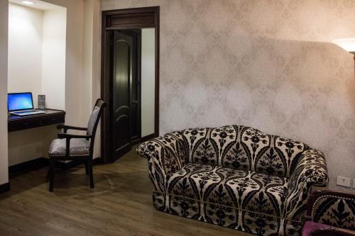 a living room with a couch and a desk and a computer at Hotel Castilla Real in Pereira