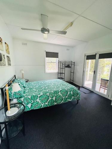 a bedroom with a green bed and a table at Bonnydoon at Hat Head - 5 Oak Street in Hat Head