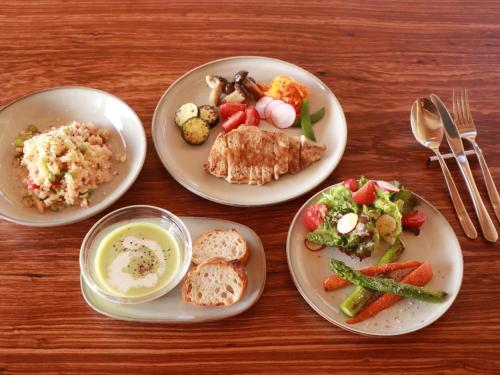 four plates of food on a wooden table at Cider Barn &more in Iida
