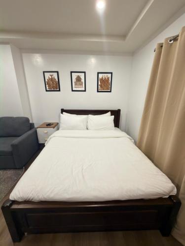 a bedroom with a large bed and a blue couch at Raya's Staycation Megatower 7 Baguio City in Baguio