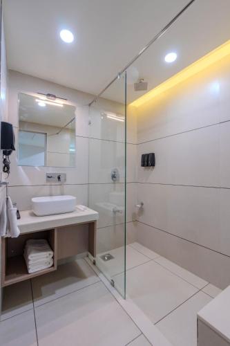 a bathroom with a sink and a glass shower at Hotel TGR in Ankleshwar
