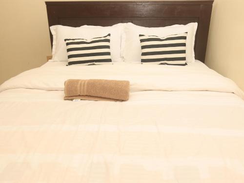 a white bed with black and white pillows and a towel at Cozy homes kisii in Kisii