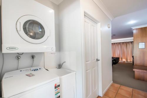 La salle de bains blanche est pourvue d'un lavabo et d'un four micro-ondes. dans l'établissement Shamrock Gardens Motel, à Mackay